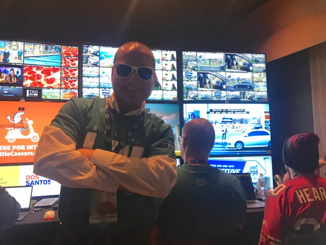 Ryan Contreras in front of a broadcast monitor wall